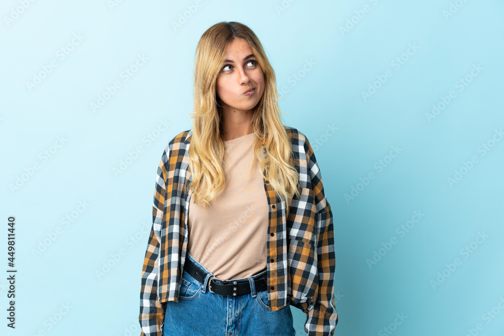 Young blonde Uruguayan isolated on blue background and looking up Young blonde Uruguayan isolated on blue background and looking up