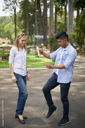 Young man explaining girlfriend how to play traditional Chinese Jianzi game and kicking special shuttlecock photo