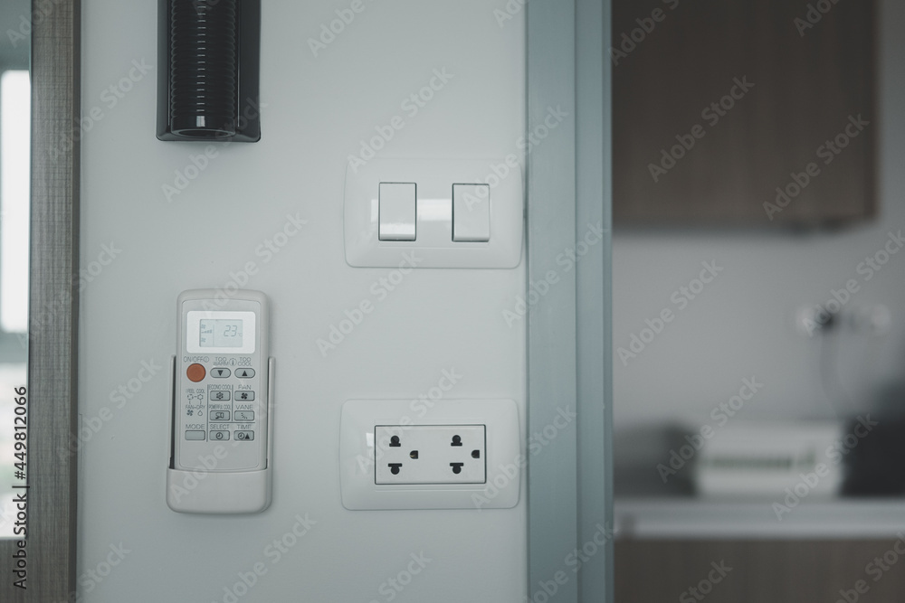 Electronics switch, power plug and air conditioner remote control on cement white wall. Electronics switch, power plug and air conditioner remote control on cement white wall.