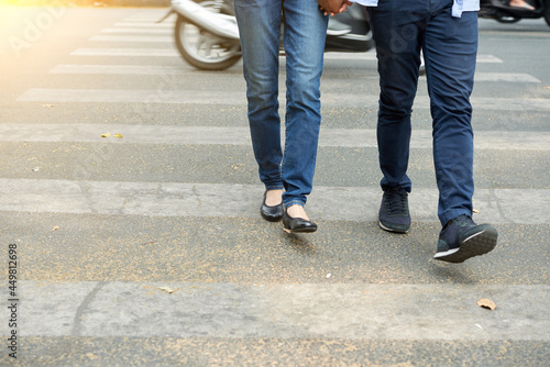 Cropped image of young couple in jeans holding hands when crossing road