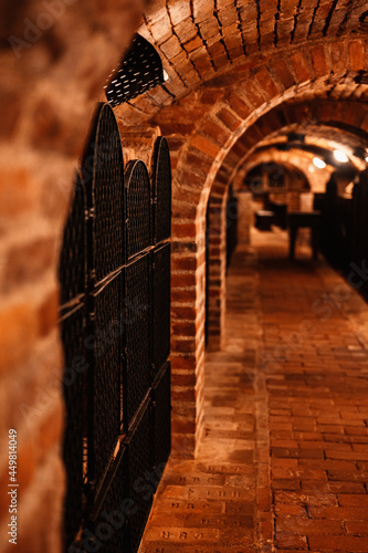 Old wine bottles dusting in an underground tratitional cellar. Small and old wine cellar with full wine bottles. Winery concept. Valtice Castle in South Moravia, Czech Republic, Europe photo