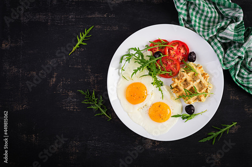 Breakfast with zucchini waffles, fried eggs, tomato, black olives and arugula on white background. Appetizers, snack, brunch. Healthy vegetarian food. Top view, overhead, copy space