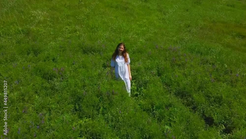 Aerial photography of a woman in a green field. A young girl walks and collects flowers in the hills. The drone flies over man and nature. Happy summer. Enjoy the moment. Run and spin, have fun. Aerial photography of a woman in a green field. A young girl walks and collects flowers in the hills. The drone flies over man and nature. Happy summer. Enjoy the moment. Run and spin, have fun.