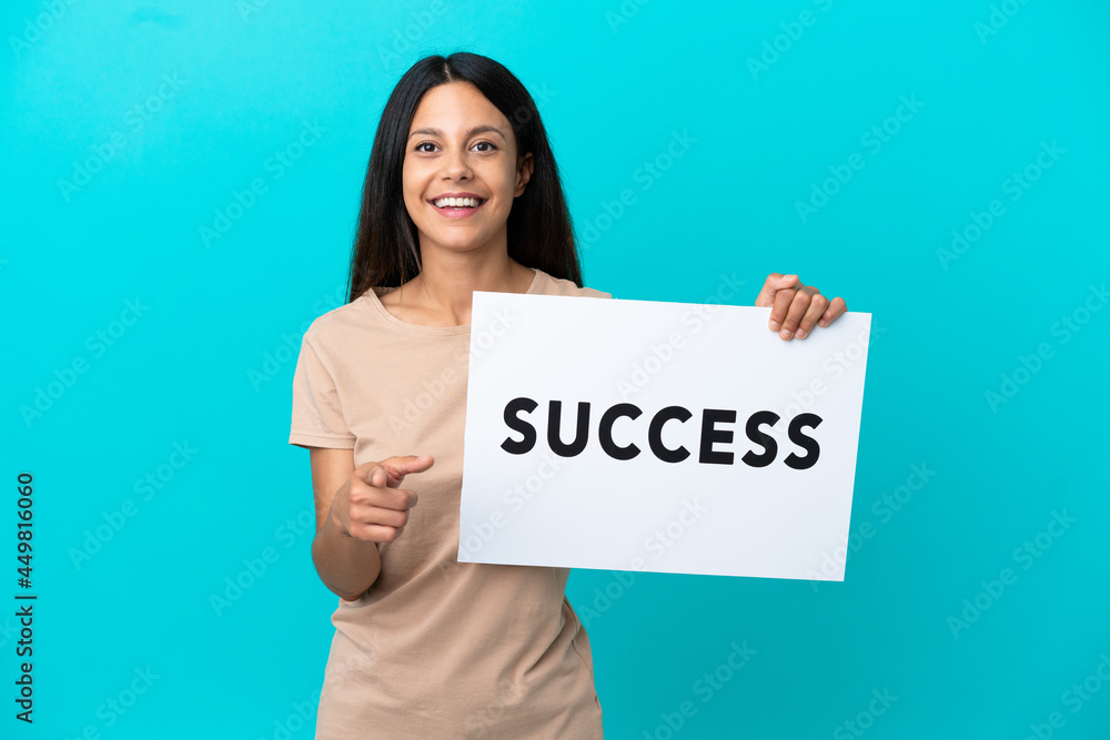 Young woman over isolated background holding a placard with text SUCCESS and pointing to the front Young woman over isolated background holding a placard with text SUCCESS and pointing to the front