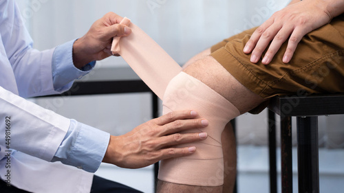 Medical concept a male doctor putting a bandage on knee's male 