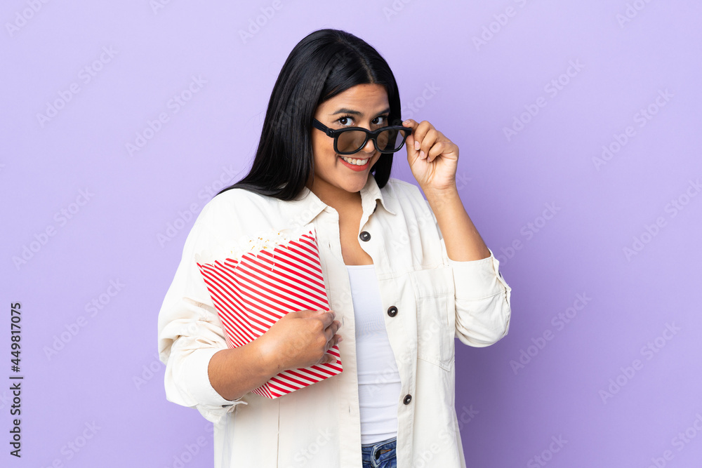 Young latin woman woman isolated on white background with 3d glasses and holding a big bucket of popcorns