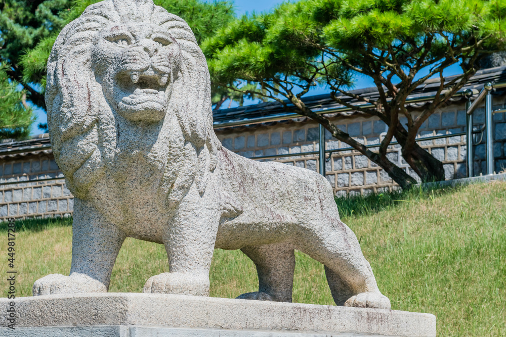 Stone carved lion on concrete plinth at entrance to public park.
