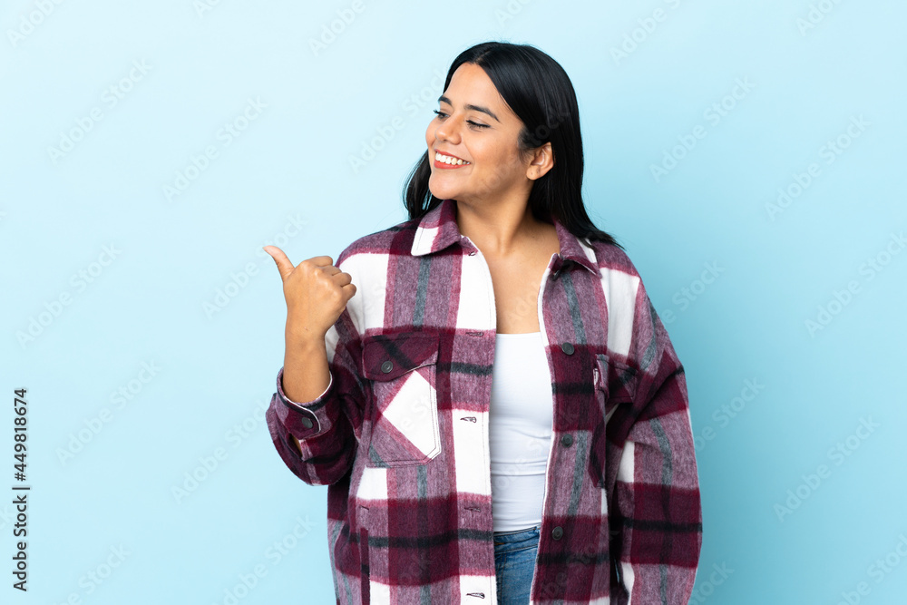 Young latin woman woman isolated on blue background pointing to the side to present a product Young latin woman woman isolated on blue background pointing to the side to present a product