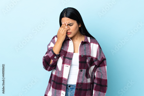 Young latin woman woman isolated on blue background with headache © luismolinero