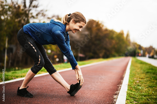 Beautiful adult woman is exercising outdoor on cloudy day in autumn.