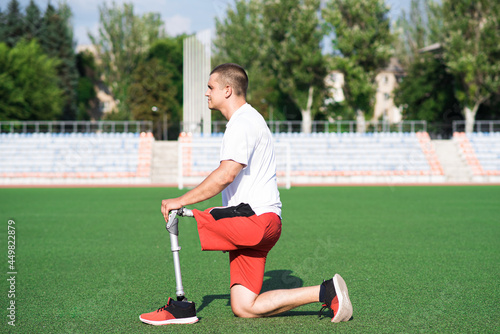 Young caucasian brunette male with prosthetic leg doing lunge at the stadium on the field. Sport concept © Павел Костенко