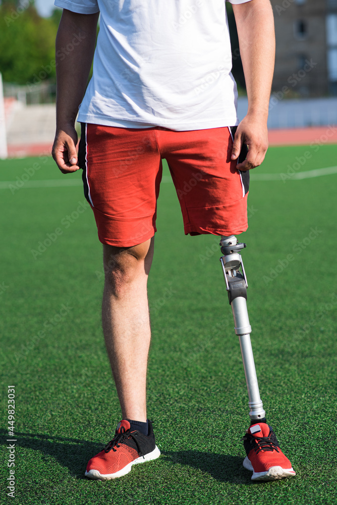 Obraz premium Close up of a man athlete with a prosthesis on his leg standing at the stadium on the field. Sport concept