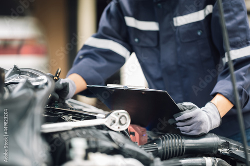 Mechanic works on the engine of the car in the garage. Repair service. Concept of car inspection service and car repair service.