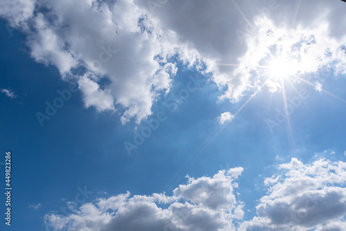 Beautiful fluffy white clouds on a blue sky with bright sun. Perfect abstract sky background