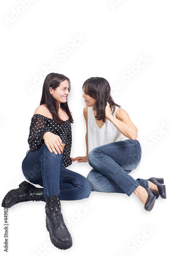 Mother and teenage daughter seated on a white background
