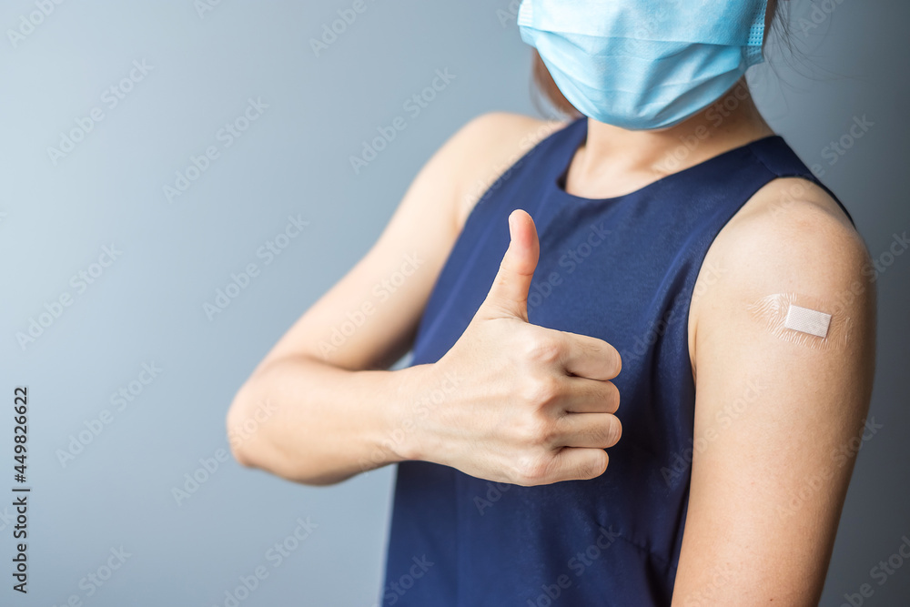 Happy woman showing thumb with bandage after receiving covid 19 vaccine. Vaccination, herd immunity, side effect, efficiency, vaccine passport and Coronavirus pandemic Happy woman showing thumb with bandage after receiving covid 19 vaccine. Vaccination, herd immunity, side effect, efficiency, vaccine passport and Coronavirus pandemic