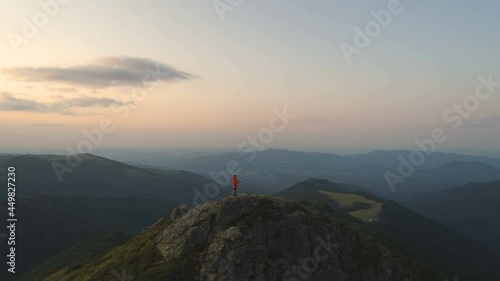 Young man hiker sitting on rocky mountain reading map, with sunset sky and deep valley below photo