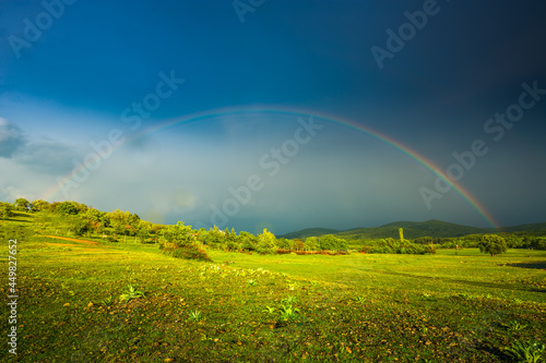 Rainbow over fields and trees on a farm on the edge of Lake