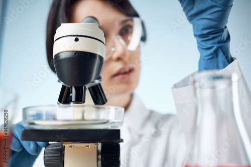 woman in laboratory adjusts microscope research analyzes technology