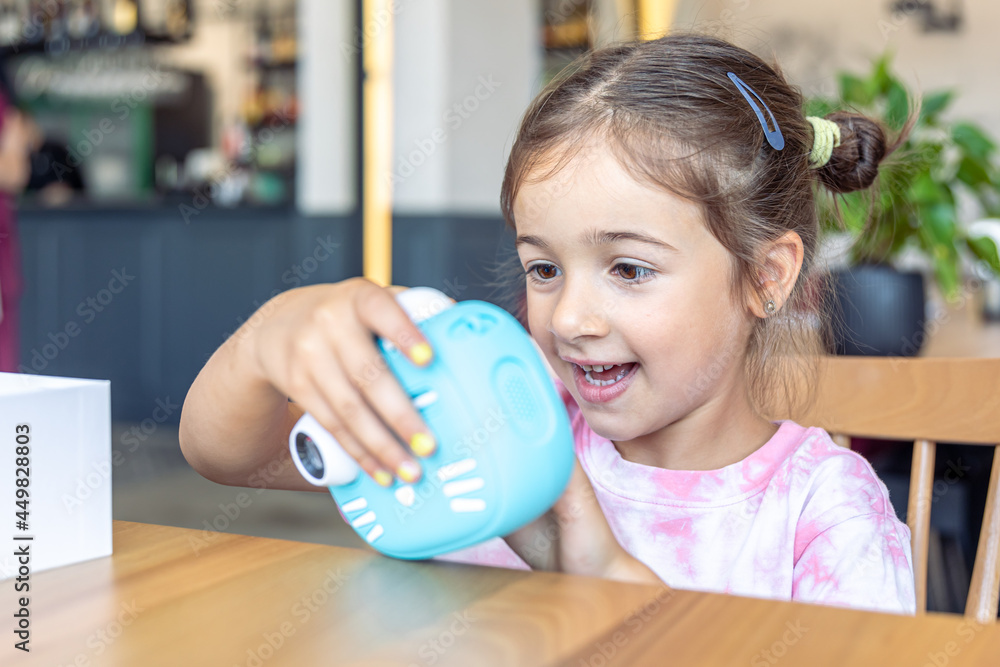 A little girl takes a photo on a camera for instant photo printing. A little girl takes a photo on a camera for instant photo printing.