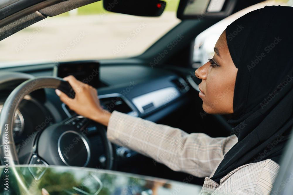 Black muslim woman looking forward while driving car Black muslim woman looking forward while driving car