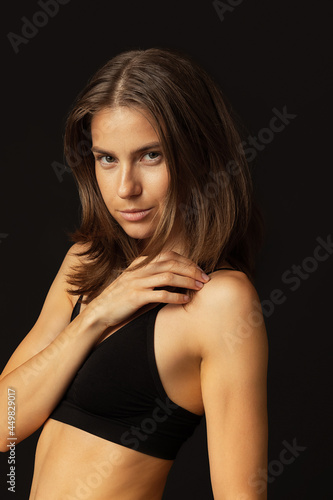 Close-up portrait of young beautiful tanned pretty woman without makeup isolated over black studio background. Natural beauty, facial emotion concept.
