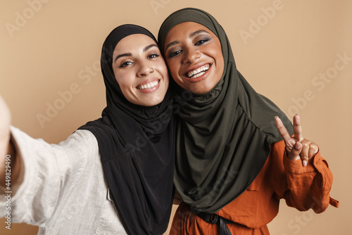Young muslim women in hijab gesturing while taking selfie photo photo