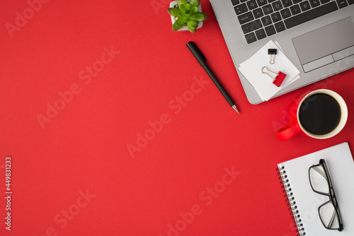 Top view photo of binder clips white sticker note paper on laptop plant pen red cup of drink and glasses on copybook on isolated red background with copyspace
