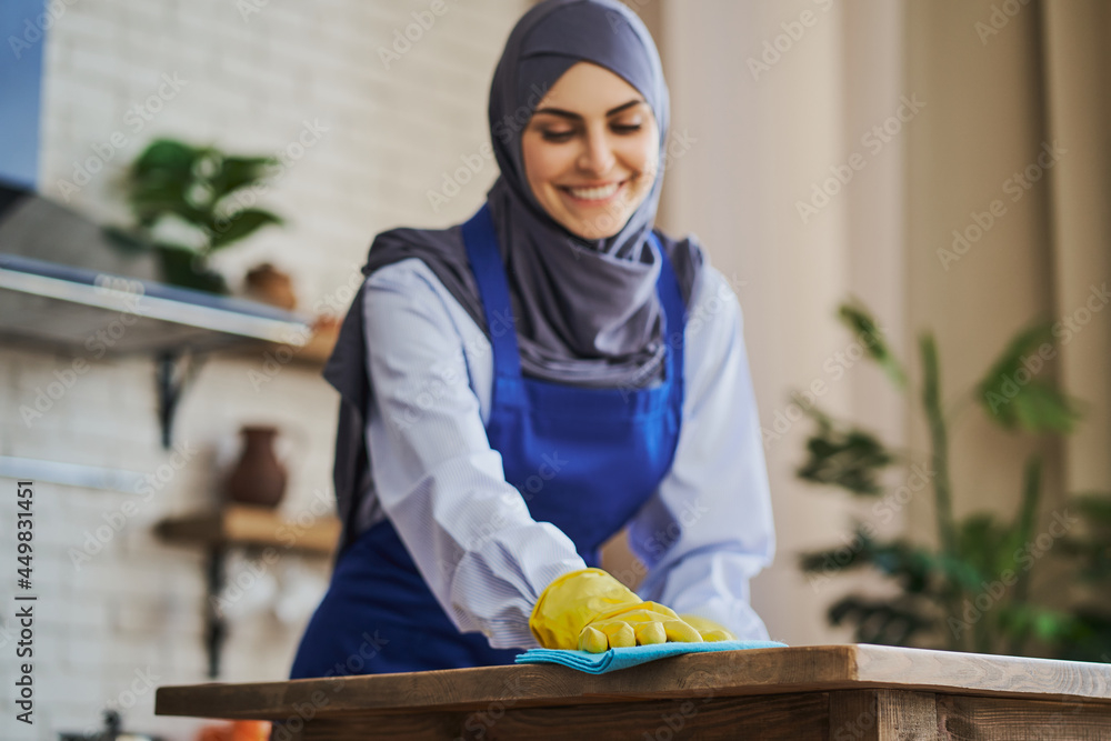 Portrait of smiling Muslim woman cleaning a house