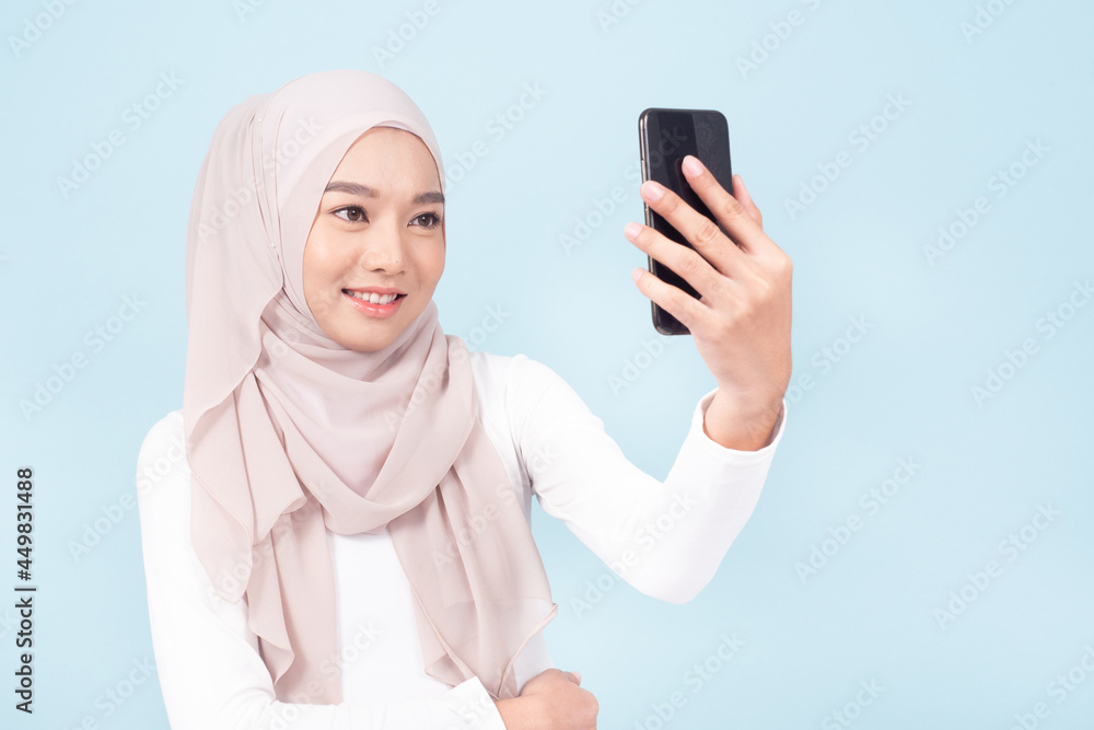 A beautiful muslim woman smiling and selfie pictures by her mobile phone. A beautiful muslim woman smiling and selfie pictures by her mobile phone.