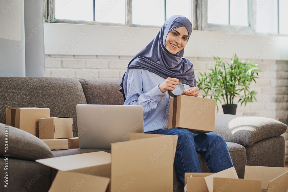 Portrait of a Muslim business woman packaging orders into cardboard boxes Portrait of a Muslim business woman packaging orders into cardboard boxes