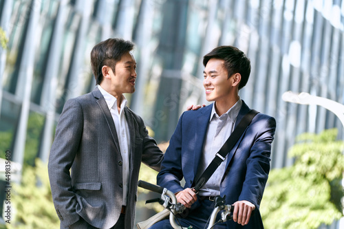 two asian business people colleagues coworkers talking on the street in downtown modern city
