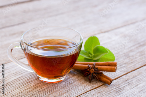 Cinnamon herbal tea in glass cup and cinnamon stick on wooden table
