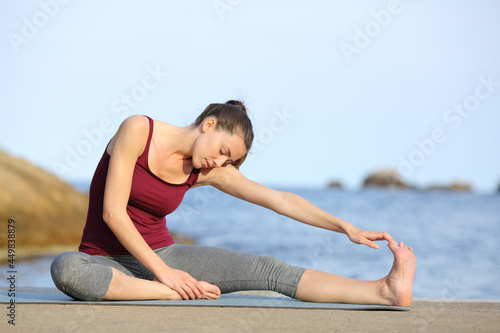 Sportswoman stretching leg after sport on the beach