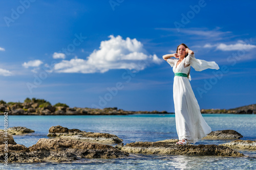 Portrait of a beautiful woman on beach with flying white dress in the wind