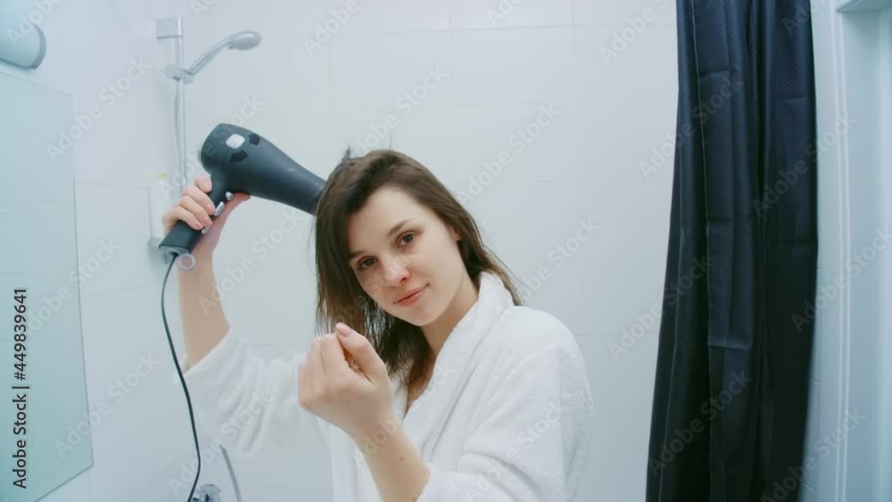 Front view of beautiful woman in white bathrobe hair dryer drying dark