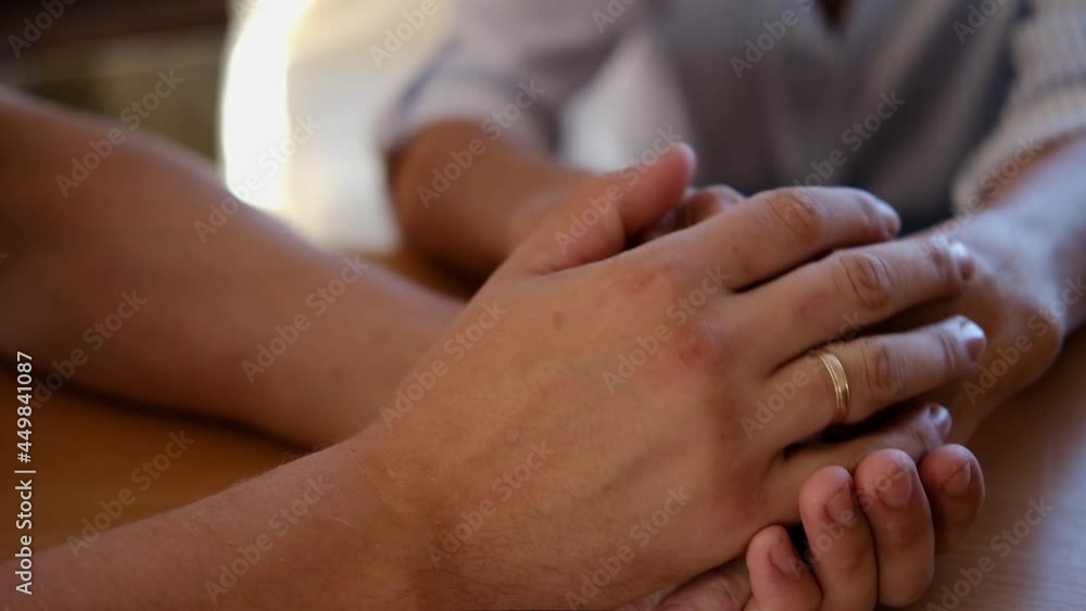 Worried caucasian man gently stroking hand of his sick old mother showing care or love. Son comforting wrinkled arm of elderly mom sitting at bed. Guy giving support to his old parent slow motion. Worried caucasian man gently stroking hand of his sick old mother showing care or love. Son comforting wrinkled arm of elderly mom sitting at bed. Guy giving support to his old parent slow motion.
