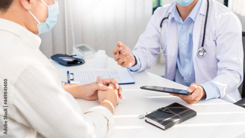Medical concept a smart male doctor wearing a mask consulting with patient about how to recover from Coronavirus outbreak (COVID-19) at his modern clinic Medical concept a smart male doctor wearing a mask consulting with patient about how to recover from Coronavirus outbreak (COVID-19) at his modern clinic