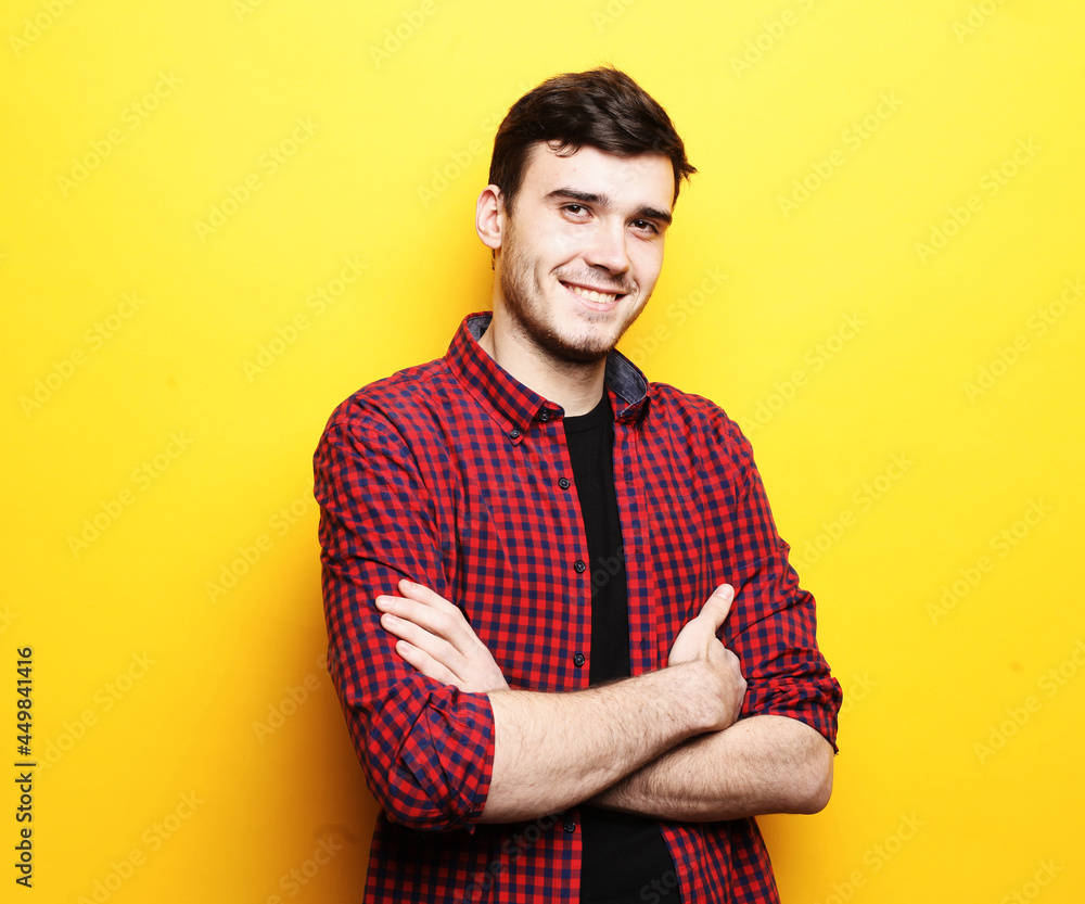 Portrait of unshaven young man wearing plaid shirt posing on camera with crossed arms hands Portrait of unshaven young man wearing plaid shirt posing on camera with crossed arms hands