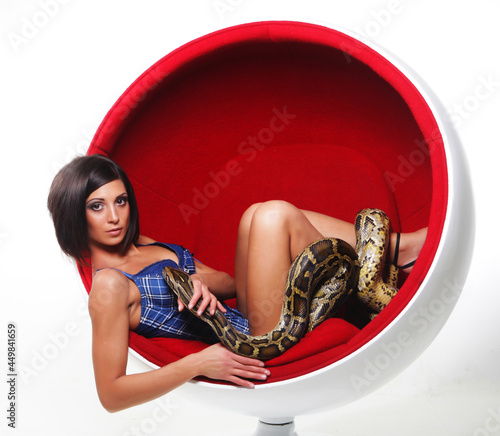 Attractive young woman in red chair holdung python, big snake.