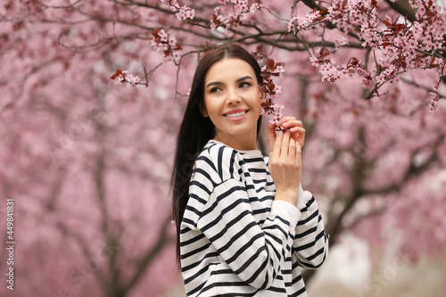 Pretty young woman near blooming tree in park. Spring look