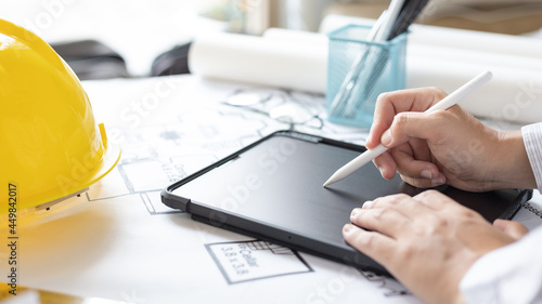 Young man using tablet plotting a system of building structures in blueprints, Architects or engineers are designing buildings using tablet to calculate the physical structure to be correct.