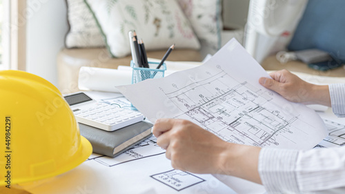 Architectural building design and construction plans with blueprints, Young man was designing a building or architecture with a ruler, pen, pencil, tape measure, architect hat and other equipment.