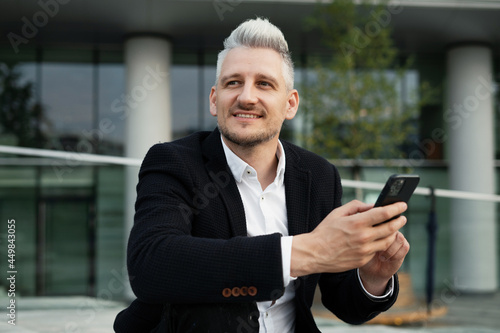 A lawyer communicates by phone with colleagues via SMS. The manager writes a response to the client by email. A businessman is a gray-haired man in a business suit sitting near the new office.