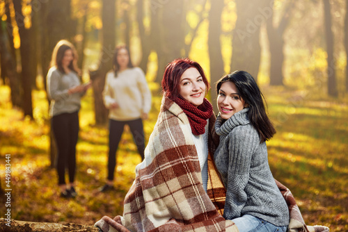 Attractive smiling women posing in forest on warm day, two female friends on the background © Denys Kurbatov