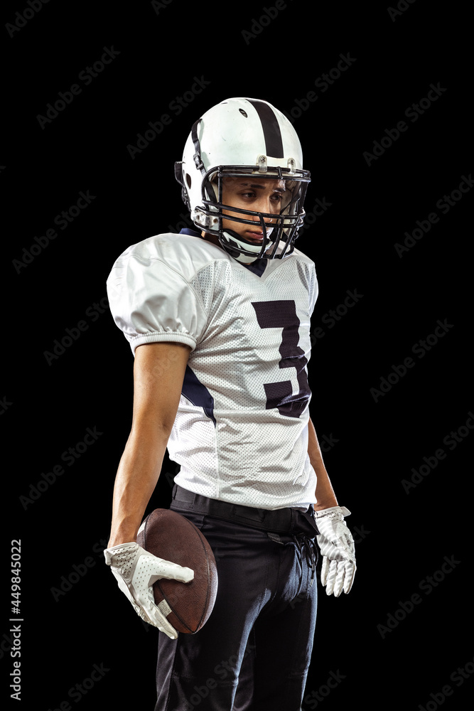 Portrait of one American football player in sports equipment helmet and gloves isolated on dark studio background. Concept of sport, competition