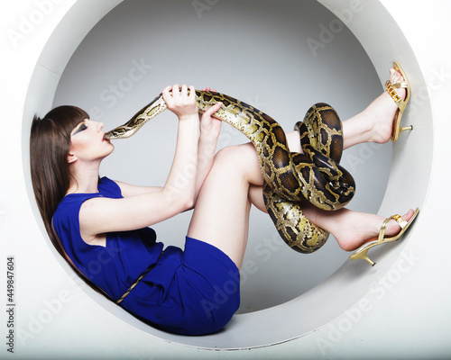 Attractive young woman in red chair holdung python, big snake.