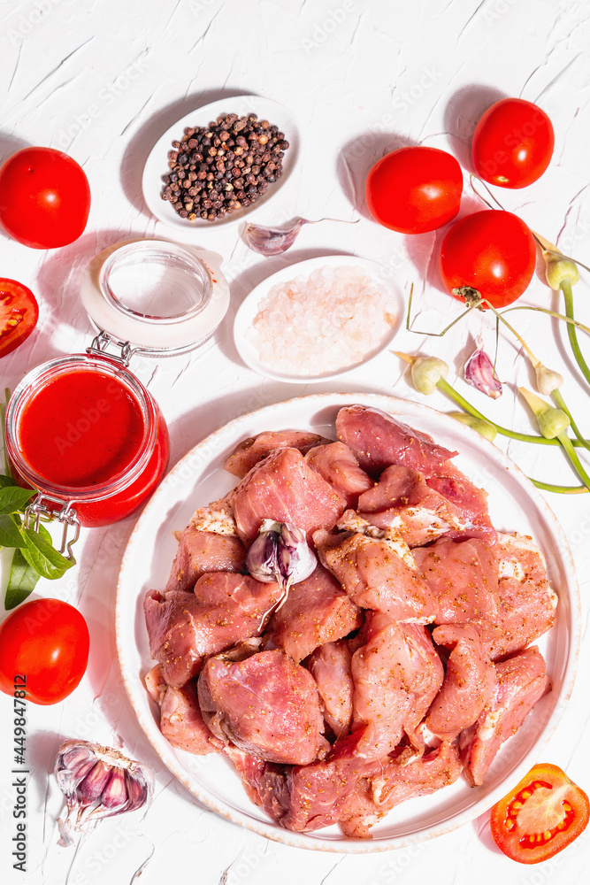 Raw pork pieces, tomatoes, spices, and herbs Raw pork pieces, tomatoes, spices, and herbs