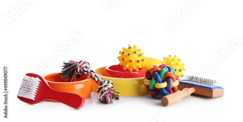 Feeding bowls, brushes and dog toys on white background photo