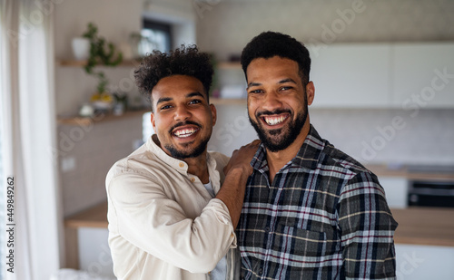 Young adult brothers in kitchen indoors at home, looking at camera.